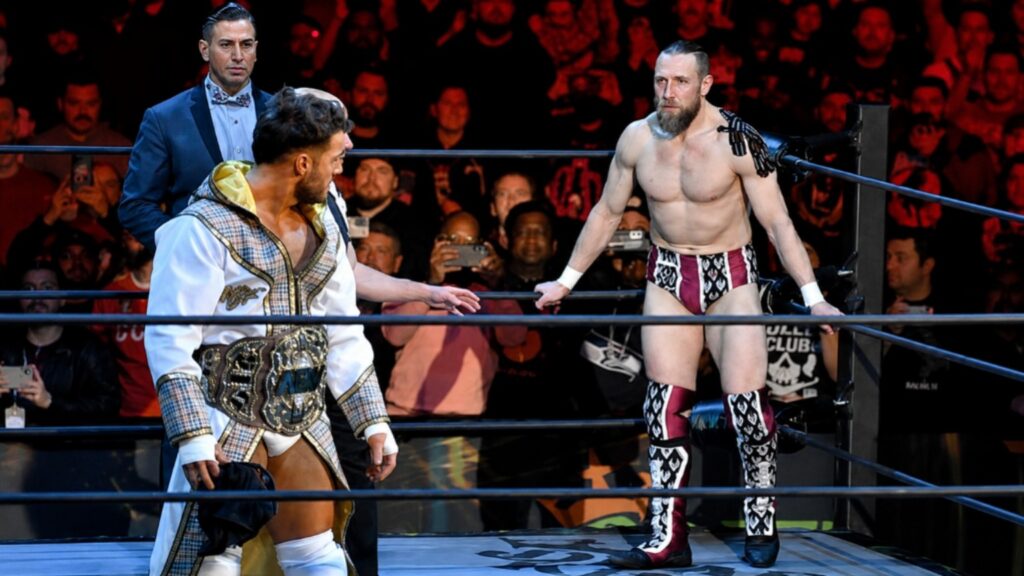 MJF confronts Bryan Danielson inside the AEW ring during an intense championship face-off while the referee watches closely before their match.