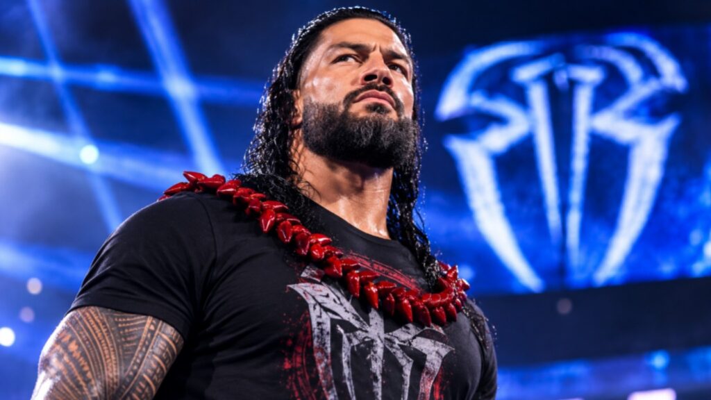 Roman Reigns standing confidently inside a WWE arena with his signature Tribal Chief look, wearing a red ula fala and black T-shirt under dramatic blue arena lights.