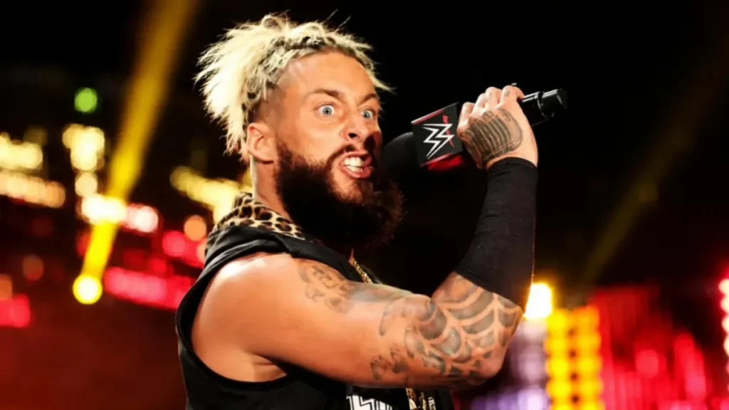 Enzo Amore delivering an intense WWE promo during a live arena appearance, shouting into the microphone with an aggressive expression.